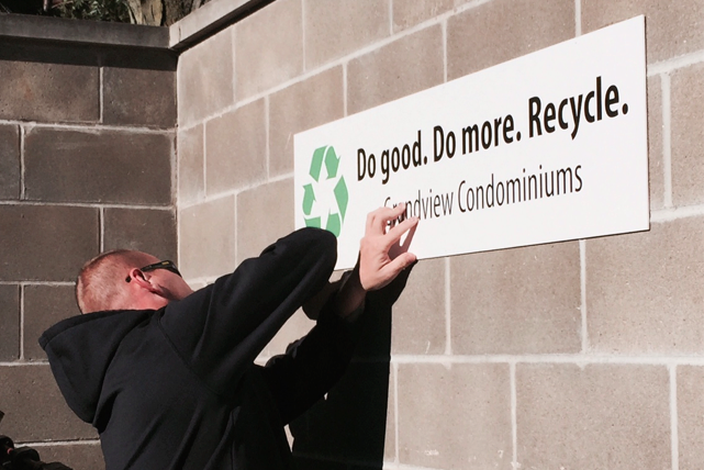 Man putting up sign encouraging recycling